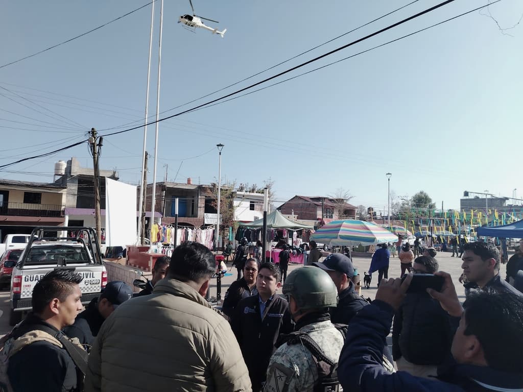 En una plaza pública, Salvador J. Vazquez Villa coordina con personal de seguridad mientras un helicóptero sobrevuela.