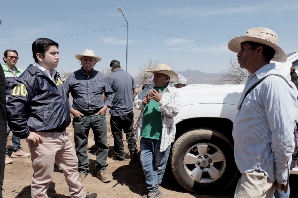 Salvador J. Vazquez Villa talks with farmers next to a pickup truck.