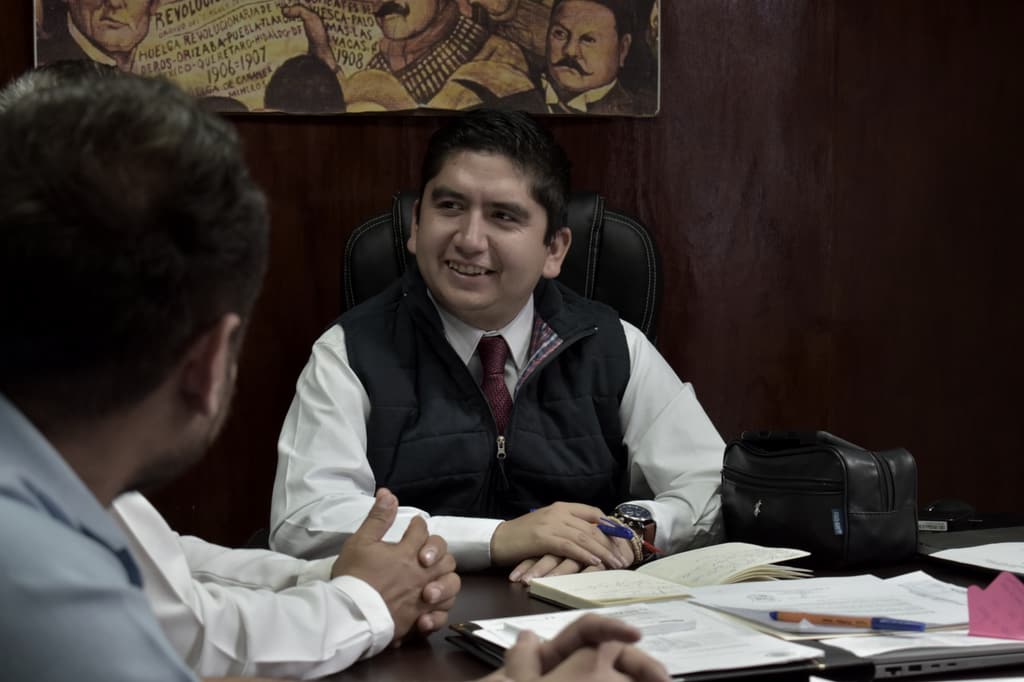 Salvador J. Vazquez Villa, smiling, talks with a counterpart during an office meeting.